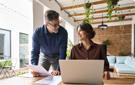 Duas pessoas trabalhando juntas em um laptop em um escritório moderno